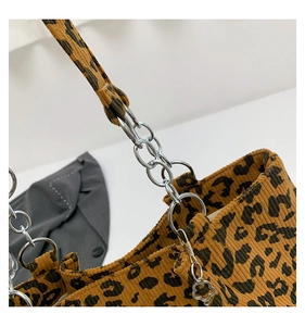 Close-up of leopard print corduroy tote bag featuring silver chain and floral pendant