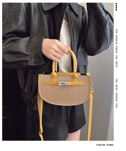 Detailed view of half-moon straw bag with yellow leather straps and silver metal lock