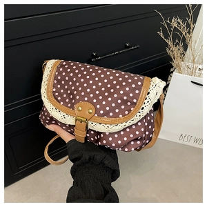 Close-up of retro brown polka dot bag with lace trim and leather metal buckle detail