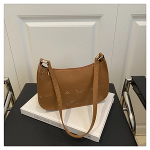 Detail of a brown snake-textured faux leather shoulder bag on a decorative book