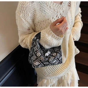 Detail of black New Chinese style hobo bag with silver floral patterns and bead clasp