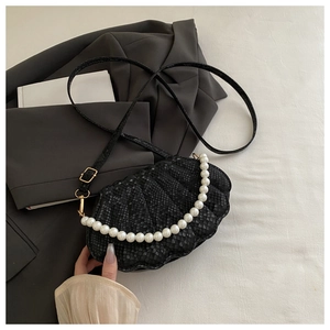 Detail of black shell crossbody bag featuring pearl strap and textured leather finish