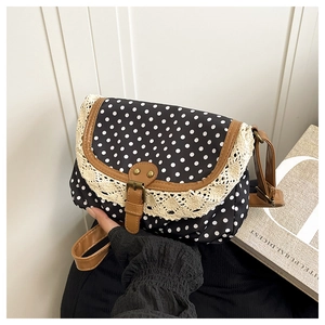 Close-up of retro polka dot canvas bag with delicate lace trim and faux leather strap