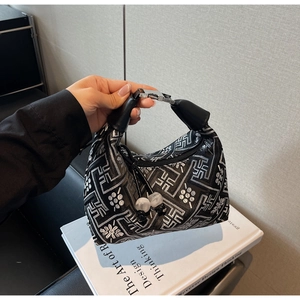 Detail of black and silver dumpling bag with geometric floral embroidery and bead charm