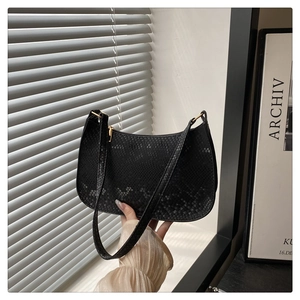 Close-up of black snake pattern texture on half-moon shoulder bag with gold zipper