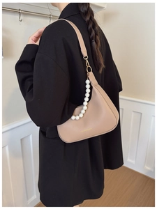 Detail of a beige pearl shoulder bag with luxury beads and fashion logo on model