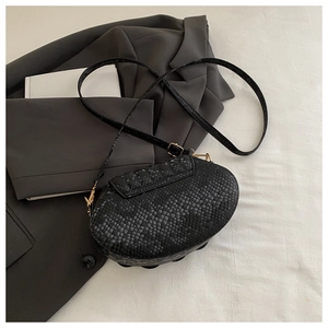 Detail of black oval shell bag featuring premium crocodile embossed texture and gold buckle