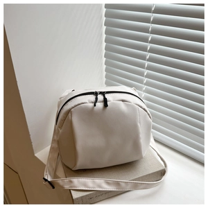Detail of off-white nylon crossbody shell bag with contrasting black double zippers
