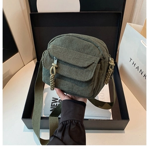 Detail of army green corduroy crossbody bag with textured zipper pull and canvas strap