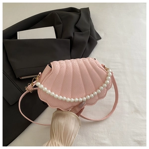 Close-up of pink shell-shaped shoulder bag with snakeskin texture and pearl strap detail