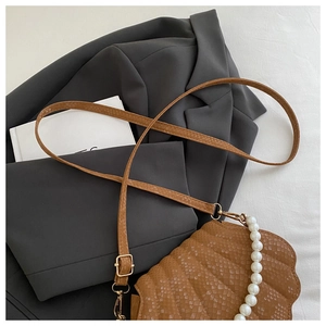 Close-up of brown snake-textured shell bag with large pearl handle and gold hardware