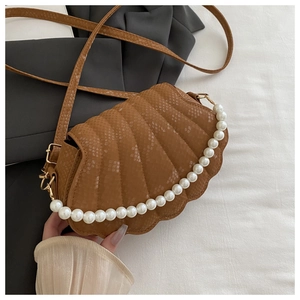 Detailed view of a brown snakeskin shell bag featuring decorative oversized white pearls