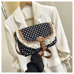 Detail of retro polka dot canvas bag with lace trim and brown leather buckle