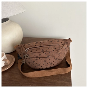Detalle de riñonera de pana marrón con motivos de corazones sobre una mesa de madera