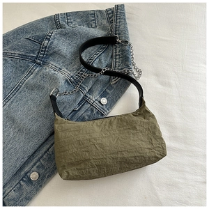 Detail of army green pleated shoulder bag with silver chain on denim background