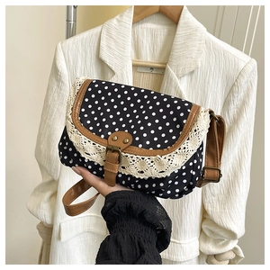Detailed close-up of polka dot canvas bag with beige lace trim and brown leather straps