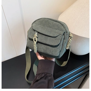Gros plan détaillé d'un sac bandoulière en velours côtelé vert foncé avec détails tissés