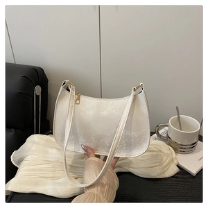 Detailed view of white snake-textured underarm bag with gold zipper and strap