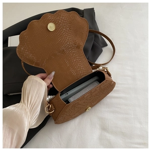 Detail of brown shell bag showing faux snakeskin texture and elegant pearl handle