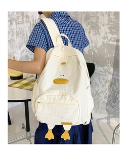 Detail of white cartoon duck backpack with yellow plush feet and 3D beak accents