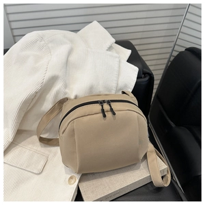 Detail of a beige canvas crescent crossbody bag with black dual zippers and strap