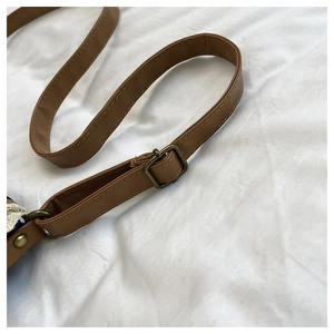 Detail of adjustable brown leather strap with bronze metal buckle on a shoulder bag