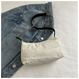 Detail of white textured mini bag with black leather strap and silver chain accent