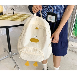 Detail showing cartoon duck backpack with yellow beak and 3D feet in a casual setting