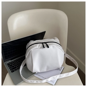 Gros plan sur le sac bandoulière blanc en nylon avec fermetures noires et large sangle