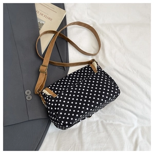 Detail of polka dot crossbody bag featuring a brown strap and vintage metal buckle