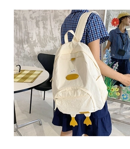Detail view of a cute 3D duck-shaped white canvas backpack with orange feet on a model
