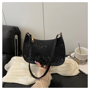 Close-up of black snake pattern texture on a crescent shoulder bag with gold hardware