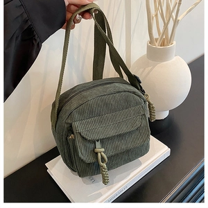 Détail d'un sac bandoulière en velours côtelé vert armée avec bandoulière réglable et tissu
