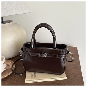 Détail du sac en cuir verni marron foncé avec boucle vintage et bandoulière rétro