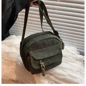Détail d'un sac bandoulière vintage en velours olive avec fermeture éclair à nœud tressé