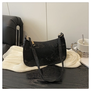 Detail of black faux snake pattern texture and gold zipper on a chic shoulder bag