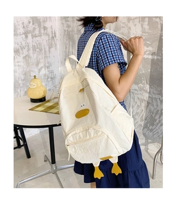 Detailed view of cream-white backpack with cute 3D cartoon duck features on a model