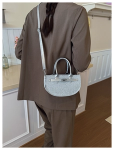 Silver sequined crescent handbag worn with a brown blazer showing adjustable strap