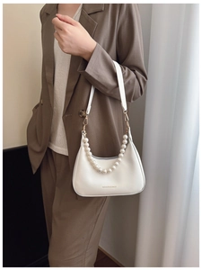Detail of white hobo bag featuring decorative pearl chain and brand logo on leather