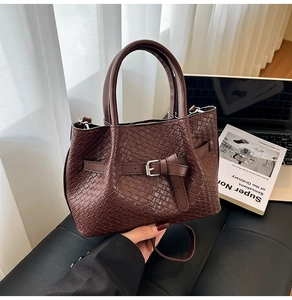Gros plan détaillé sur la texture tressée marron foncé et la boucle argentée du sac seau