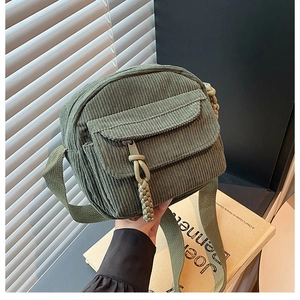 Détail d'un sac bandoulière en velours côtelé vert avec poche à rabat et sangle
