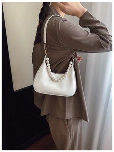 Close-up of white crescent underarm bag featuring elegant large pearl chain accessories