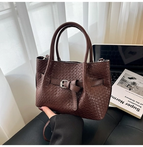 Dettaglio della borsa a mano marrone scuro intrecciata con fibbia e finitura in ecopelle premium