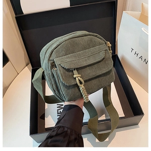 Détail de la texture en velours côtelé vert olive et poche frontale du sac bandoulière