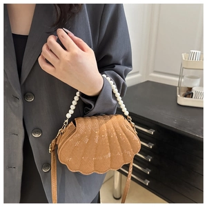 Detail of shell-shaped faux leather bag with snake texture and pearl handle