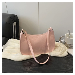 Detail shot of the pink snakeskin textured shoulder bag on a stylish dark wood surface