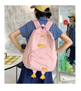 Pink cartoon duck backpack worn by a model in a cozy cafe setting for teen girls