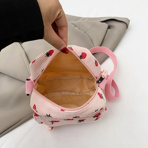 Pink corduroy mini crossbody bag with strawberry pattern showing inner lining and strap