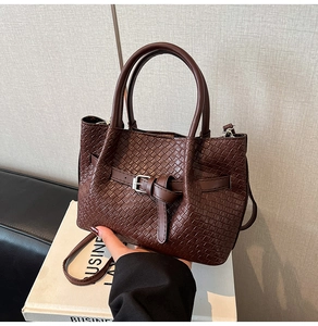 Dettaglio borsa marrone scuro con trama intrecciata e manici tondi in metallo