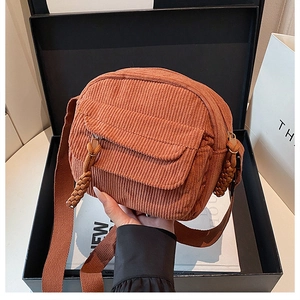 Detail of vintage corduroy crossbody bag with front flap pocket and woven zipper puller